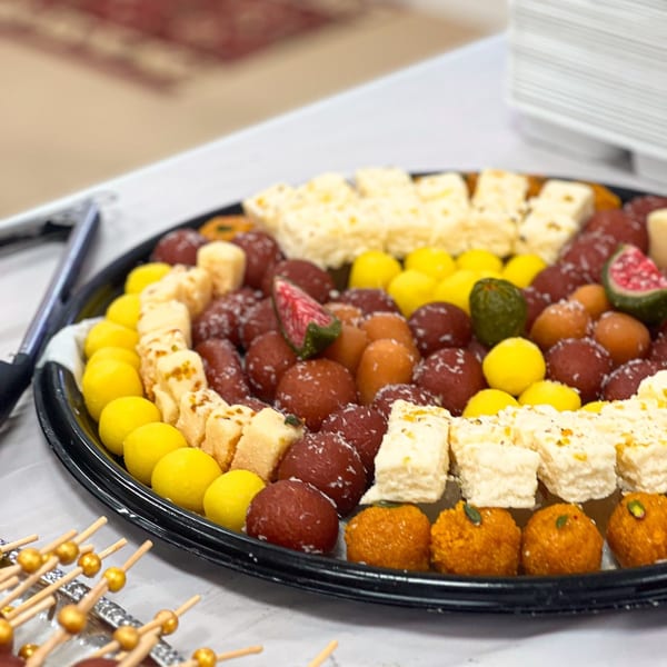 A platter of colorful Indian sweets, including gulab jamun, ladoo, and barfi, from Taste of Punjab.